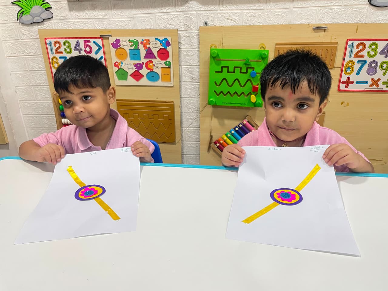 Two children proudly showing their handmade rakhi craftwork