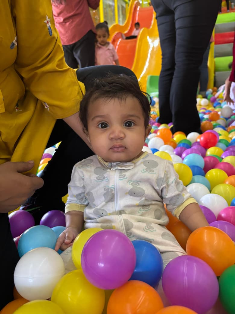 Little child playing happily in a colourful ball pit
